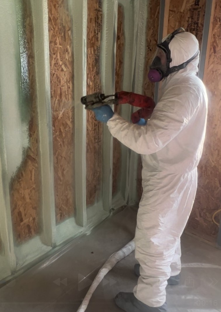 Installer applying spray foam insulation at a rim joist